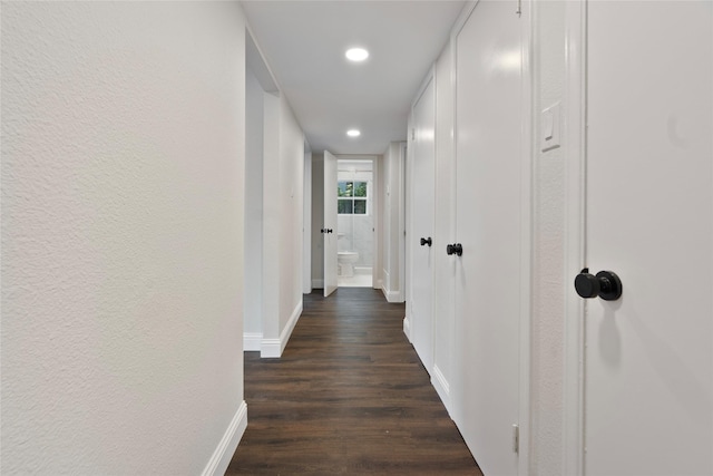 corridor with dark wood finished floors, recessed lighting, baseboards, and a textured wall