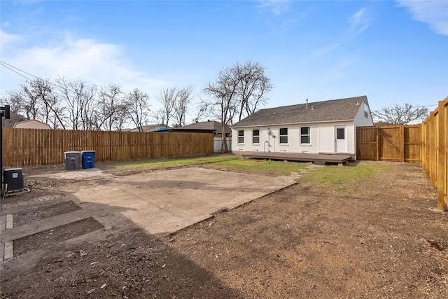 rear view of property with a patio area, a wooden deck, and a fenced backyard