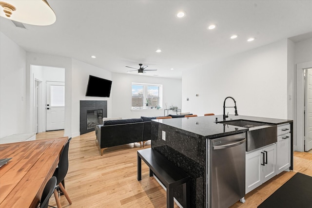 kitchen with a glass covered fireplace, stainless steel dishwasher, light wood-style flooring, and recessed lighting