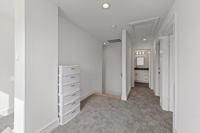 hall with visible vents, baseboards, attic access, carpet flooring, and recessed lighting