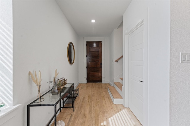 hall featuring stairway, light wood-style flooring, and baseboards