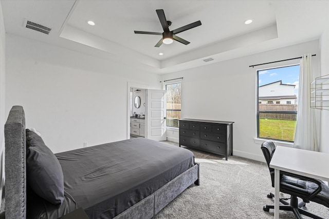 carpeted bedroom with a tray ceiling, baseboards, and visible vents