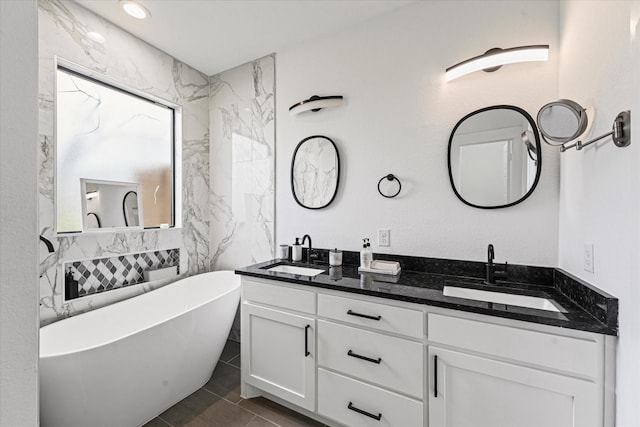 full bath with double vanity, tile patterned floors, a freestanding bath, and a sink