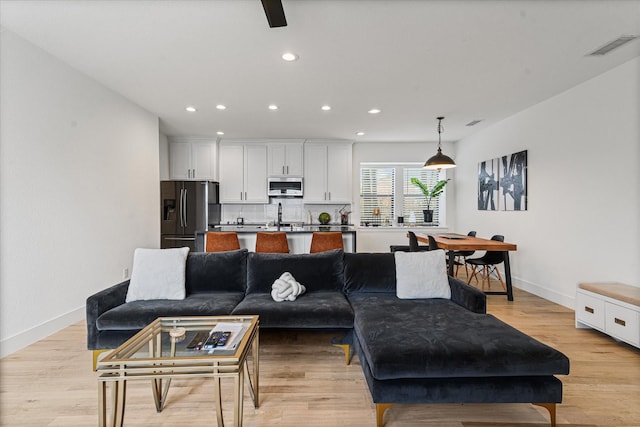 living area with visible vents, recessed lighting, light wood-type flooring, and baseboards