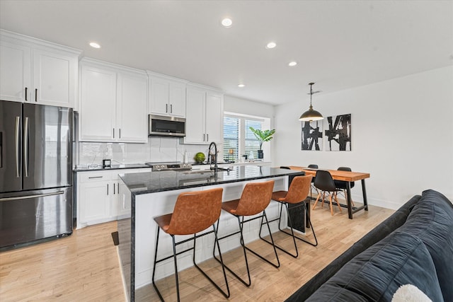 kitchen featuring decorative backsplash, a kitchen breakfast bar, light wood-type flooring, and appliances with stainless steel finishes