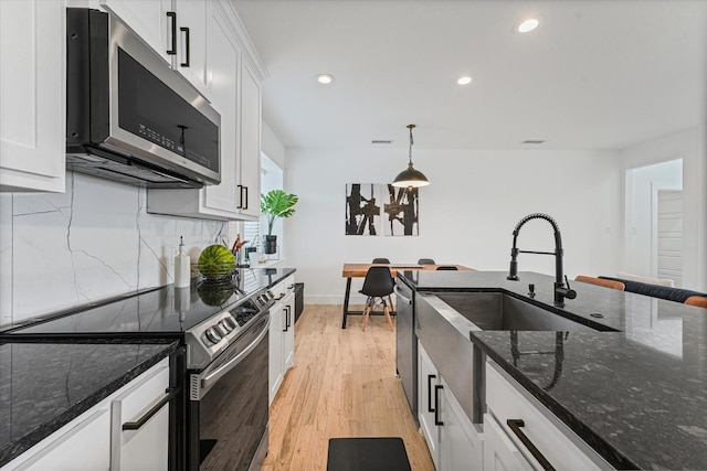 kitchen featuring tasteful backsplash, appliances with stainless steel finishes, white cabinets, and light wood finished floors