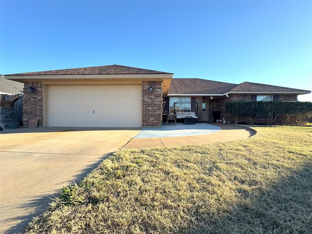 single story home with brick siding, concrete driveway, a garage, and a front yard