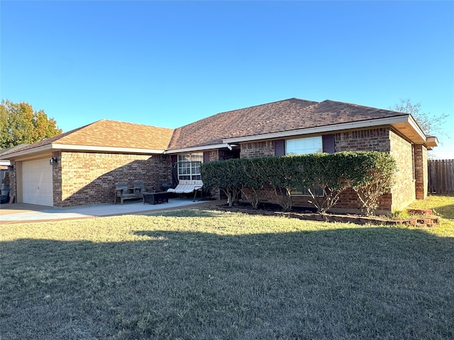 back of property featuring a yard, fence, brick siding, and an attached garage