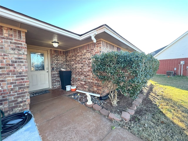 entrance to property featuring cooling unit and brick siding