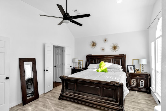 bedroom featuring a ceiling fan, baseboards, visible vents, light wood finished floors, and high vaulted ceiling