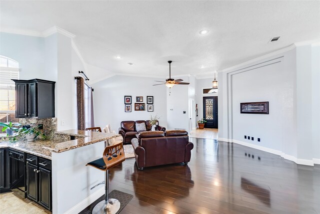 living area featuring ornamental molding, a ceiling fan, wood finished floors, a barn door, and baseboards