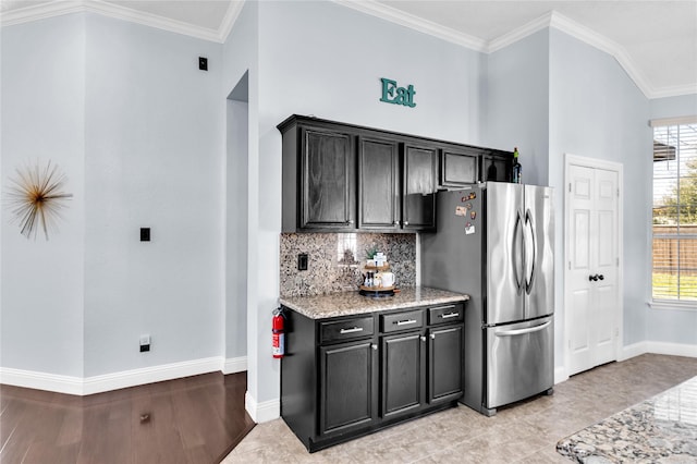 kitchen with tasteful backsplash, a healthy amount of sunlight, freestanding refrigerator, and ornamental molding