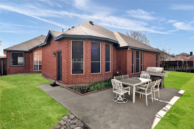 back of property with a yard, fence, brick siding, and a patio area