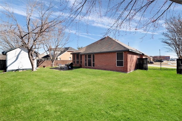 rear view of house featuring a patio, brick siding, a lawn, and fence