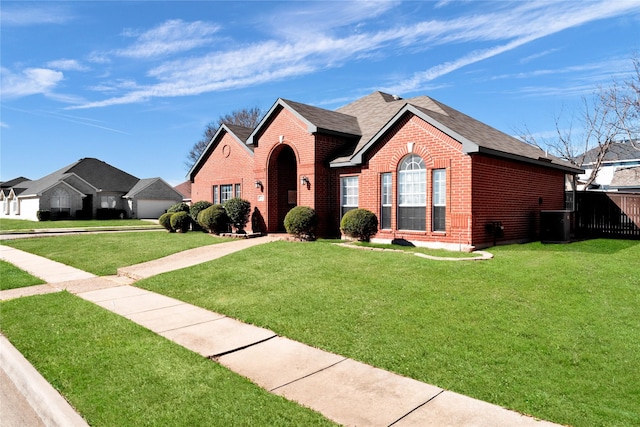 view of front of property featuring brick siding, a front lawn, and roof with shingles