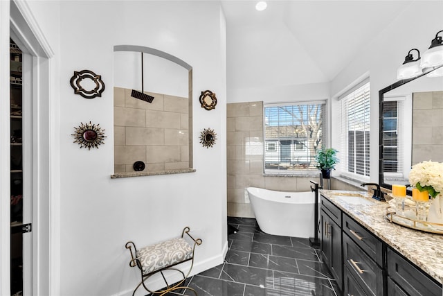 bathroom with tile walls, a soaking tub, walk in shower, vanity, and vaulted ceiling