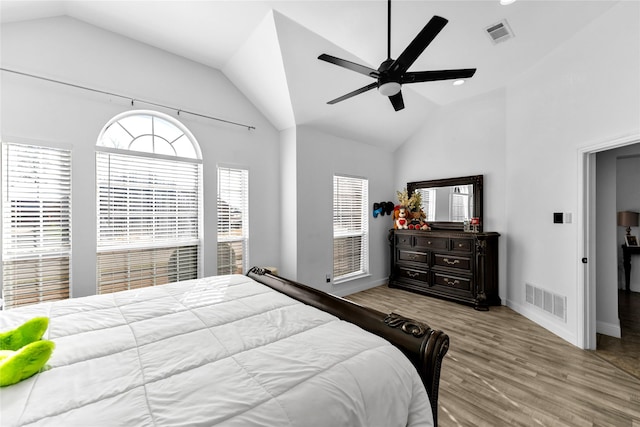 bedroom with visible vents, high vaulted ceiling, baseboards, and wood finished floors