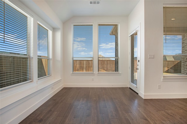 empty room featuring dark wood finished floors, visible vents, and a wealth of natural light