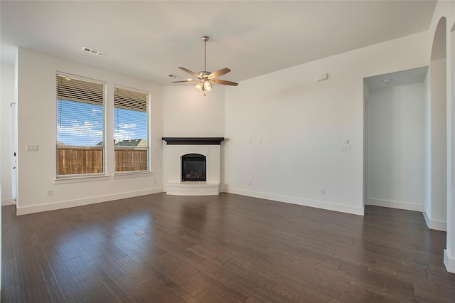 unfurnished living room featuring visible vents, dark wood finished floors, a fireplace, baseboards, and ceiling fan