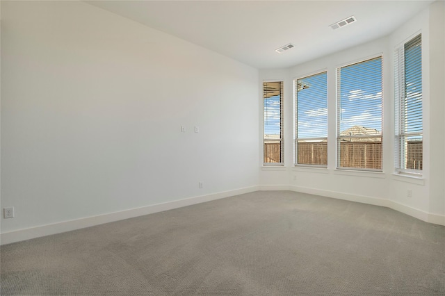 empty room featuring visible vents, baseboards, and carpet flooring