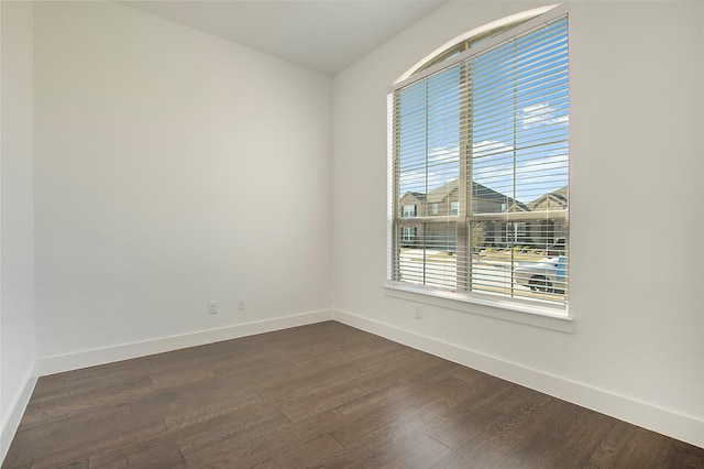 unfurnished room with baseboards and dark wood-style floors