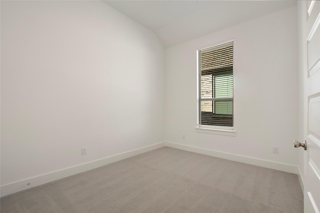 unfurnished room with light colored carpet, baseboards, and lofted ceiling