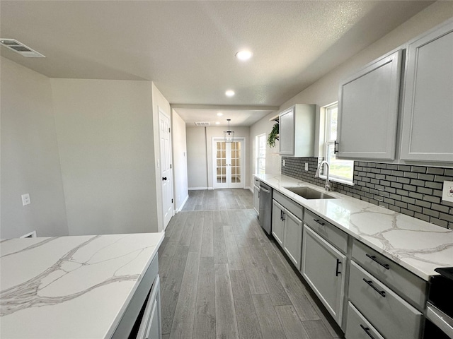 kitchen featuring visible vents, a sink, wood finished floors, appliances with stainless steel finishes, and decorative backsplash