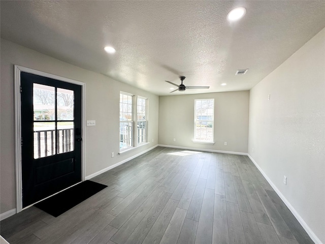 entryway featuring dark wood finished floors, visible vents, a textured ceiling, and baseboards