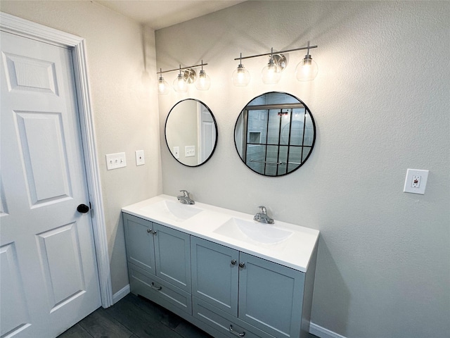 bathroom featuring double vanity, wood finished floors, baseboards, and a sink