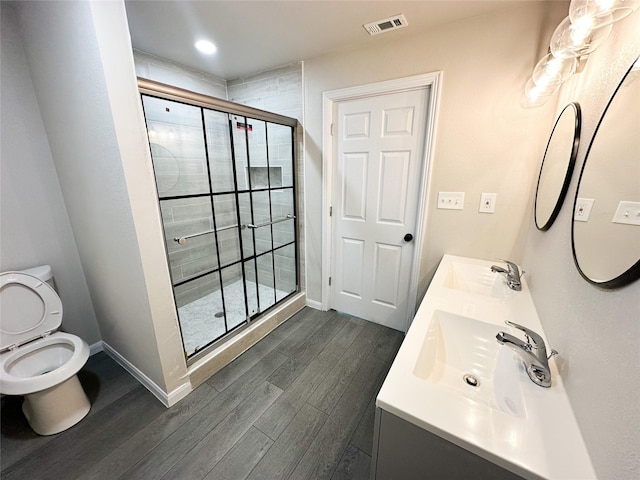 bathroom featuring wood finished floors, baseboards, visible vents, a sink, and a shower stall