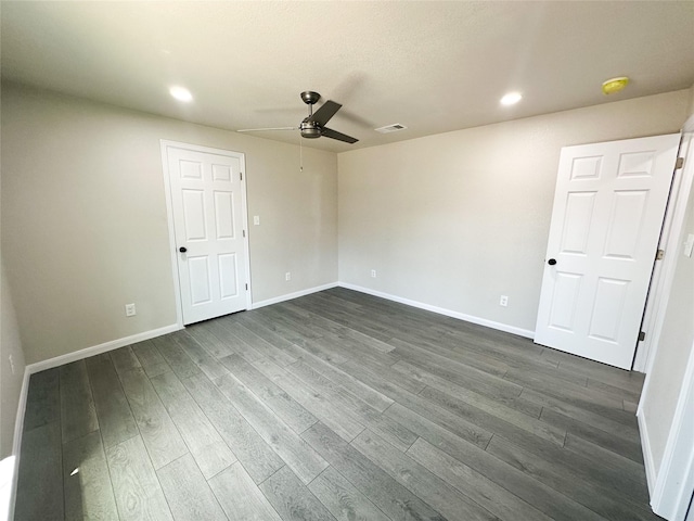 spare room featuring dark wood-style floors, visible vents, recessed lighting, and baseboards