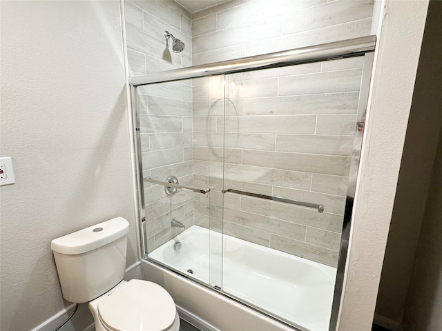 full bath with combined bath / shower with glass door, toilet, and a textured wall