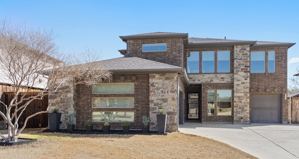view of front facade featuring stone siding, brick siding, concrete driveway, and fence