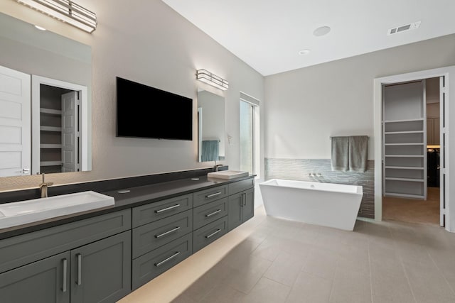 bathroom featuring a walk in closet, double vanity, visible vents, and a sink