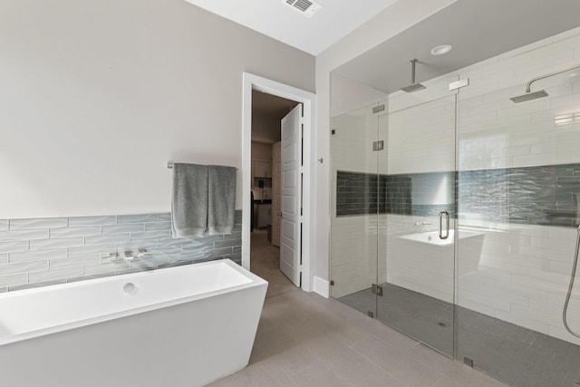 full bath featuring visible vents, a stall shower, a freestanding bath, and tile walls