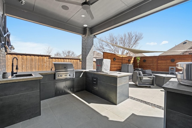 view of patio featuring a sink, area for grilling, a fenced backyard, and a ceiling fan