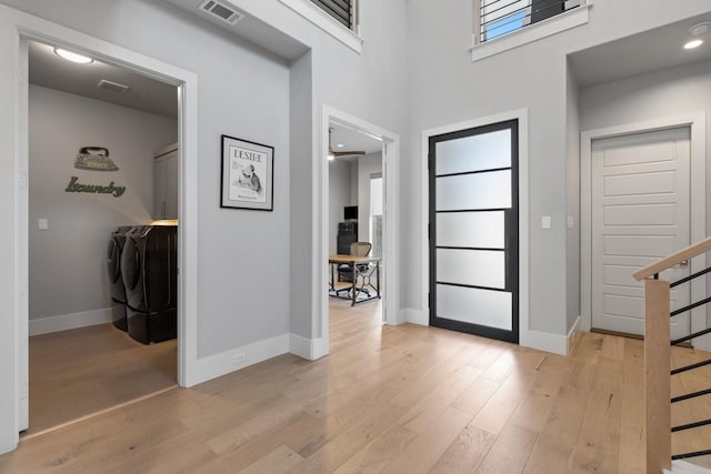 foyer entrance with visible vents, baseboards, light wood-style floors, and independent washer and dryer