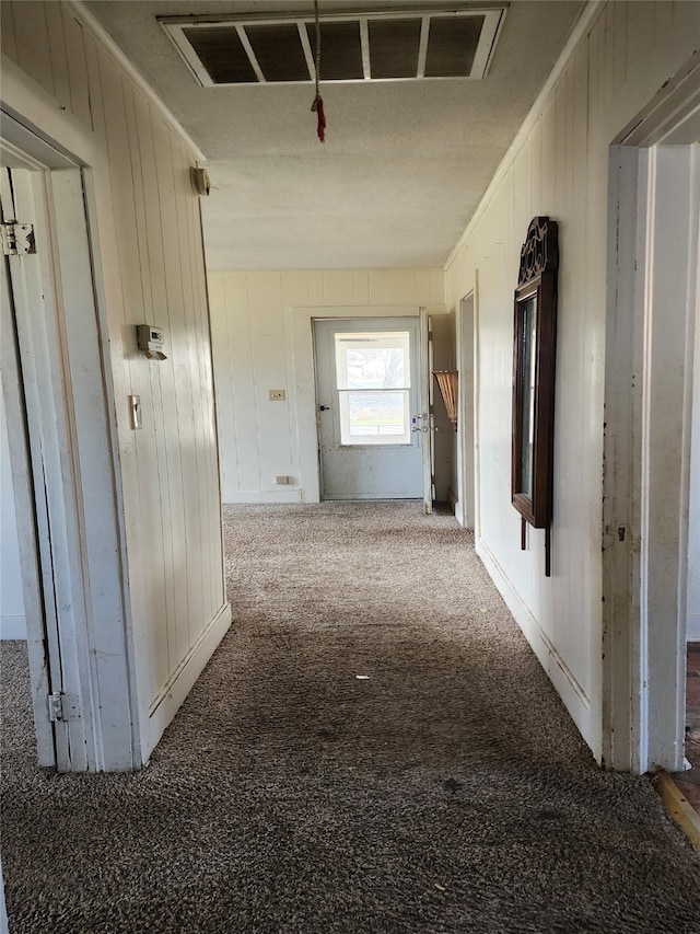 hall featuring visible vents, carpet, and wooden walls