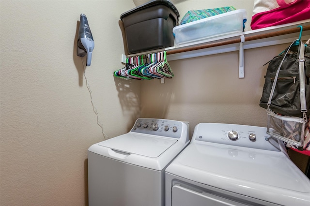 clothes washing area featuring laundry area, a textured wall, and independent washer and dryer