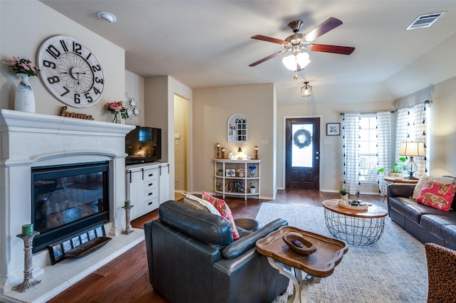 living room with visible vents, ceiling fan, baseboards, a glass covered fireplace, and dark wood-style flooring