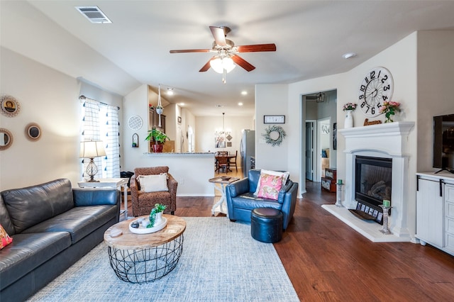 living area with a glass covered fireplace, wood finished floors, visible vents, and a ceiling fan