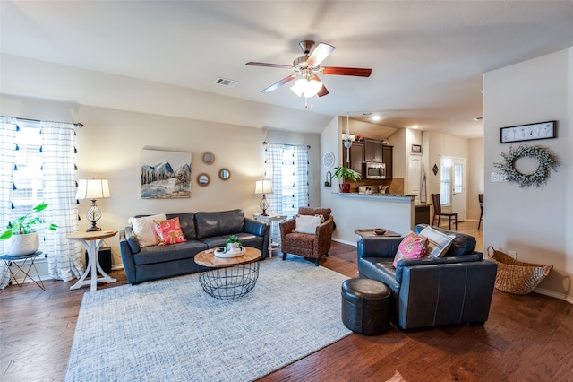 living room featuring visible vents, baseboards, ceiling fan, dark wood finished floors, and vaulted ceiling