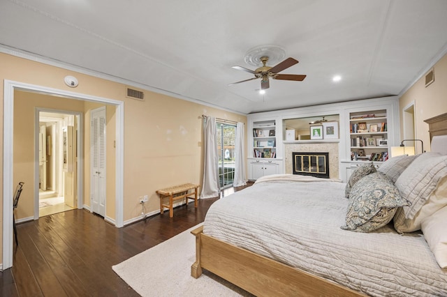 bedroom with a glass covered fireplace, dark wood-type flooring, baseboards, and visible vents