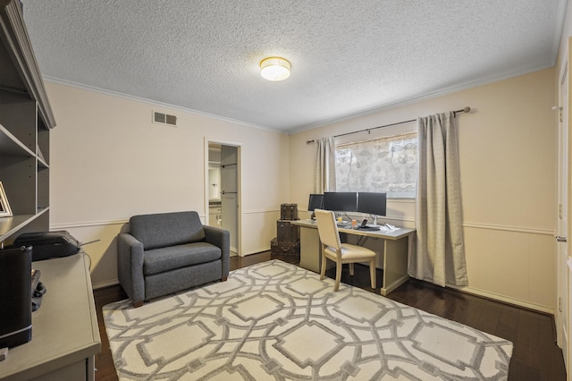 office area featuring visible vents, a textured ceiling, wood finished floors, and ornamental molding