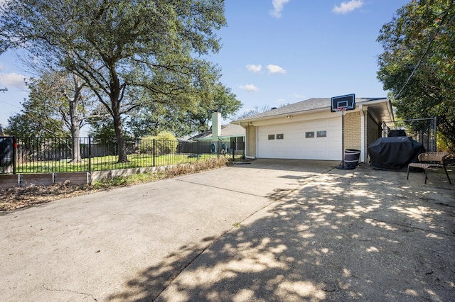 view of property exterior with brick siding, driveway, an outdoor structure, and fence