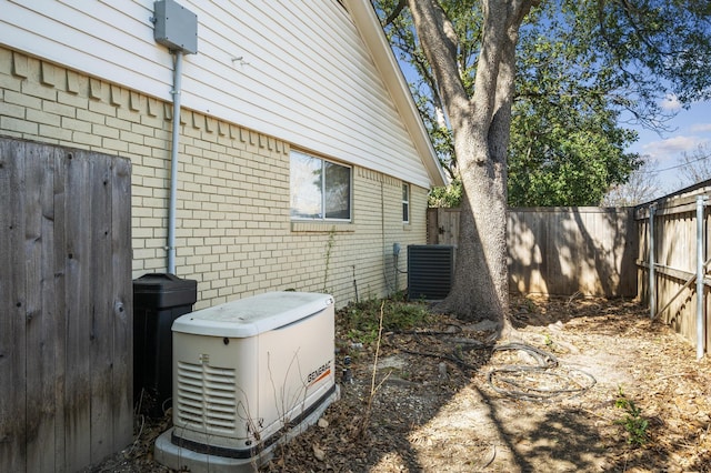 view of side of home featuring brick siding, central AC unit, and a fenced backyard