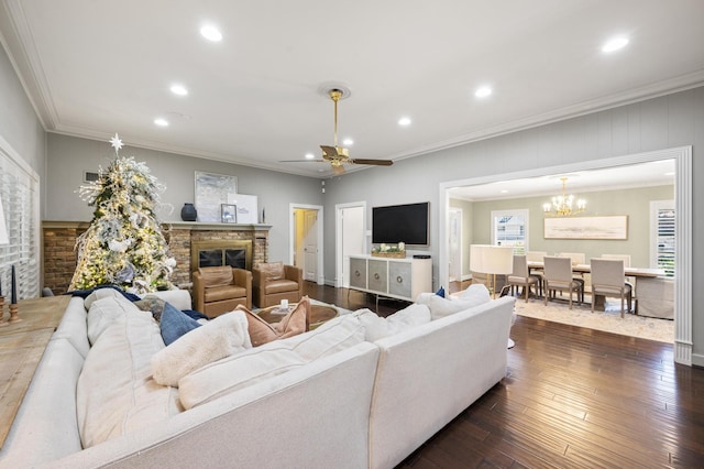 living area with dark wood-style floors, a stone fireplace, recessed lighting, and crown molding