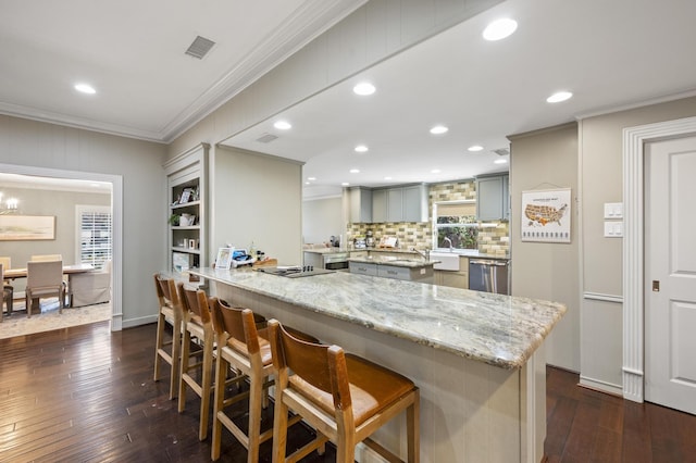 kitchen featuring stainless steel dishwasher, a peninsula, a breakfast bar area, and crown molding