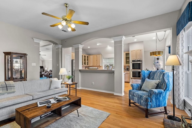 living room with light wood-type flooring, decorative columns, visible vents, and a ceiling fan