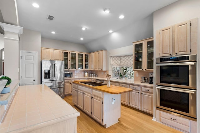 kitchen with visible vents, light brown cabinets, backsplash, a kitchen island, and appliances with stainless steel finishes